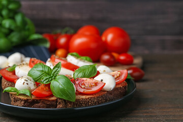 Tasty sandwiches with mozzarella cheese, tomatoes, basil and spices on wooden table against brown background, closeup