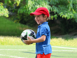  little three-year-old boy plays football at a sports school.