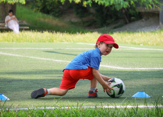  little three-year-old boy plays football at a sports school.
