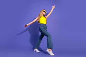 Young woman in casual attire joyfully posing against a vibrant purple background, exuding confidence, energy