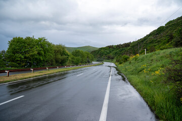 Wet road through green hills