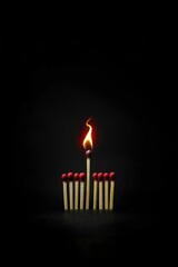 A single lit matchstick glows brightly among unlit black matchsticks, highlighting the contrast between light and darkness.