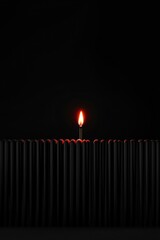 A single lit matchstick glows brightly among unlit black matchsticks, highlighting the contrast between light and darkness.