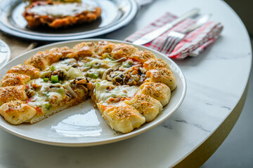 A circle of pizza on a plate with abundant cheese and toppings of vegetables and meat