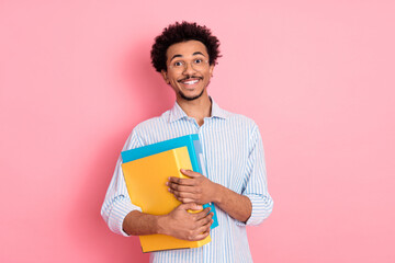 Cheerful Young Man Holding Colorful Folders with a Confident Smile on Trendy Pink Background