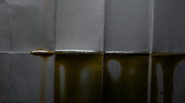 High-resolution texture of folded gray paper with visible vertical and horizontal creases, stained with dark translucent oil marks.