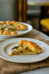 A circle of pizza on a plate with abundant cheese and toppings of vegetables and meat