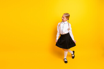 Young Schoolgirl Posing in Formal Uniform with Pigtails Over Bright Yellow Background Expressing...