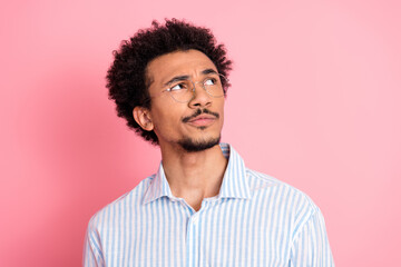 Obraz premium Young man with thoughtful expression wearing a striped shirt standing against a pink background