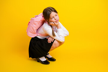 Schoolgirl in formal wear with a pink backpack, expressing thoughtful mood against a vibrant yellow...