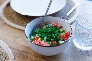 Fresh and Colorful Salad with Chopped Tomatoes and Green Onions Served in a Modern Bowl on a Wooden Table Under Soft Lighting
