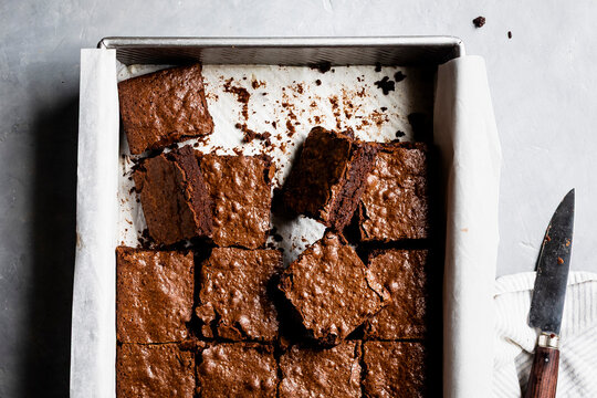 A baking tray filled with freshly cut chocolate brownies on parchment paper.