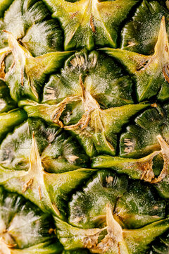 Close-up of a pineapple's textured skin with green and yellow hues.
