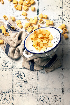 raw maccheroni in colander on tiled table