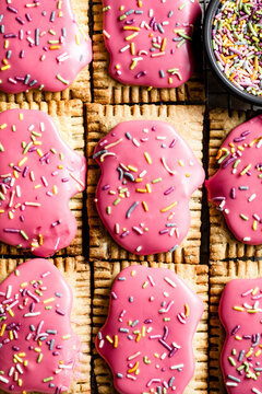 An assortment of pastries topped with pink icing and colorful sprinkles.