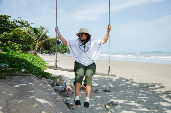 Thai woman sit and play on wooden bench swings toy at Laem Charoen beach and Mae Pim beach