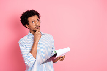 Young casual man with curly hair in a striped shirt holding documents, thinking, and looking...