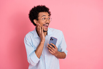 Delighted man in striped shirt holding smartphone, reflecting excitement and surprise on a vibrant...