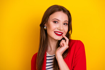 Young woman in red blazer posing happily against vibrant yellow background, showcasing elegance and...
