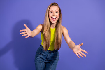 Cheerful young woman in vibrant casual attire spreading arms with an inviting smile in front of a...