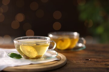 Cups of tasty green tea with lemon on wooden table, closeup