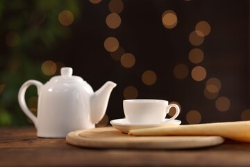Cup of tasty tea and teapot on wooden table