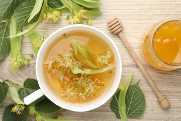 Fresh linden tea in cup, honey and flowers on wooden table, flat lay