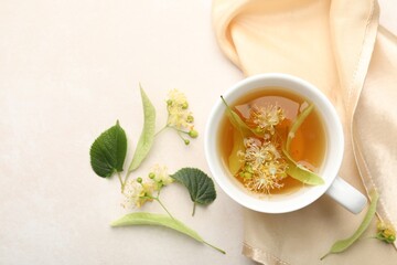 Fresh linden tea in cup and flowers on white table, flat lay. Space for text