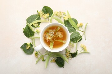 Fresh linden tea in cup and flowers on white table, flat lay