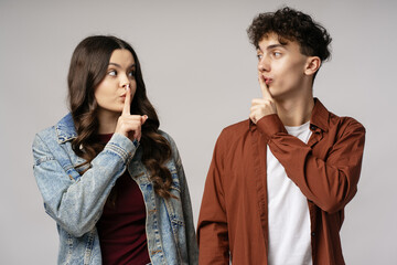 Young Couple Making Silence Gesture with Finger on Lips