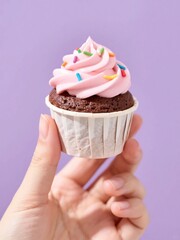 Chocolate cupcake with pink frosting, hand-held dessert mockup for celebration and bakery branding