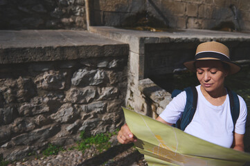 Tourist Exploring a Historic Stone Landmark While Studying a Map Outdoors