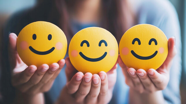 A woman holding three smiley face emojis in her hands.