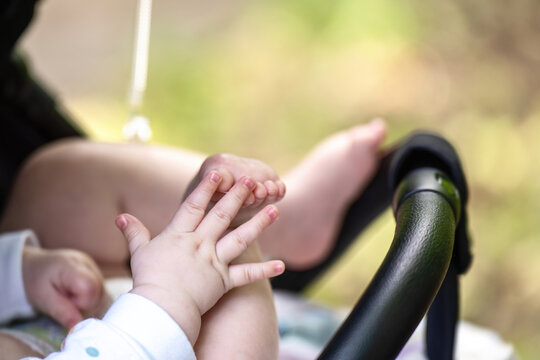 Baby in stroller demonstrates early development stage - hand-foot interaction, a precursor to crawling