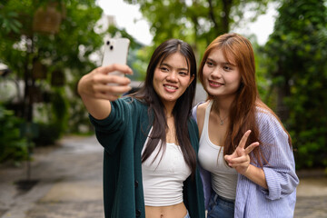 Fototapeta premium two young women talking on the phone in park