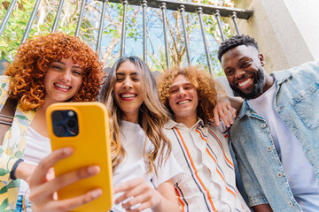 Diverse college friends taking selfie outdoors, radiating happiness, sharing camaraderie and joy under bright sunlight, showcasing multicultural bond