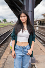 Young woman at railway station looking at camera wearing jeans
