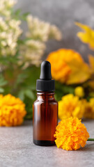 Amber glass dropper bottle with marigold flower, natural skincare concept