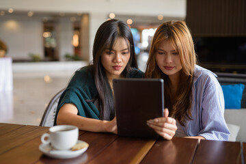 two women using tablet computer in cafe