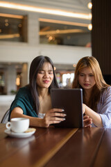 two women in cafe using tablet computer
