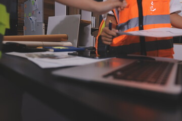 Closeup of team of industrial engineers meeting analyze machinery blueprints consult project on table in manufacturing factory. Working in manufacturing plant or production plant.