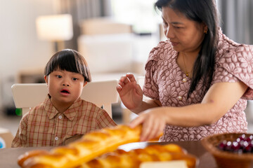 Caring mother gently comforts her child with Down syndrome at the dining table, creating a moment...