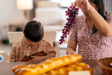 Caring mother gently comforts her child with Down syndrome at the dining table, creating a moment...