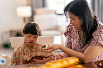 Caring mother gently comforts her child with Down syndrome at the dining table, creating a moment...