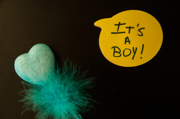 Photograph of a yellow emoji on a black background with  "It´s a boy "written inside.