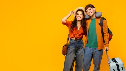 Portrait of happy European couple traveling, ready for vacation, posing with suitcase on yellow...
