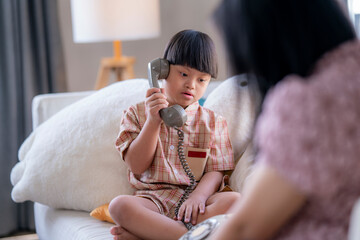 Young child with Down syndrome exploring an old-fashioned telephone handset, engaging in playful...