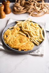 Plate of beef milanesa, cotoletta or schnitzel with side fries