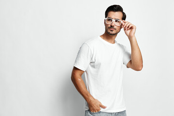 Stylish young man in white t-shirt and trendy glasses looking confident while posing against a...