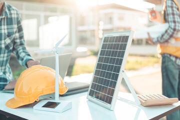 Two engineers work on wind turbine model components and discuss renewable energy sources of the...